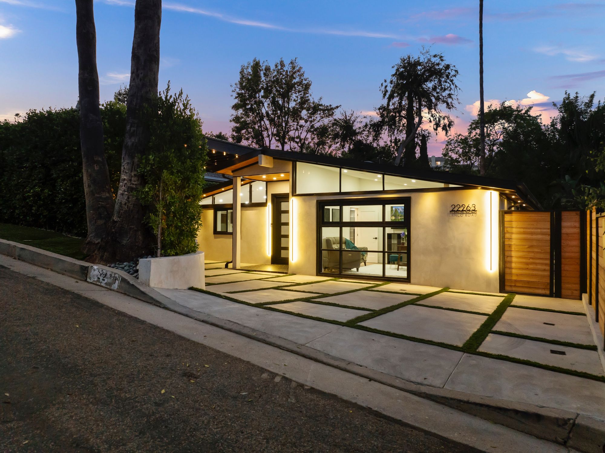 Streetfront approach to the residence at dusk, mature California foliage framing the entry path.