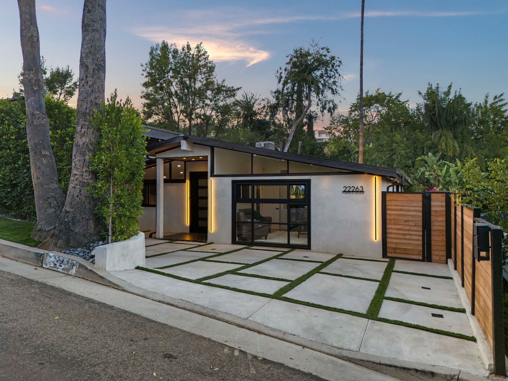 Resort-style backyard at twilight: jetted pool, waterfall spa, fire features, and full outdoor kitchen.